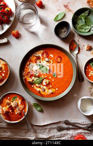 Cremige Tomatensuppe auf hellem beigem Marmorhintergrund Stockfoto