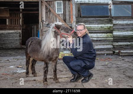 Eine Tierschutzinspektorin teilt einen herzerwärmenden Moment der Verbindung mit einem Miniatur-Pony und strahlt Sorgfalt und Mitgefühl aus Stockfoto