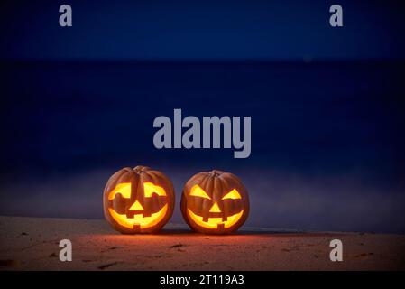 Halloween-Kürbisse jagen am Strand bei Nacht im hellen Mondlicht Stockfoto