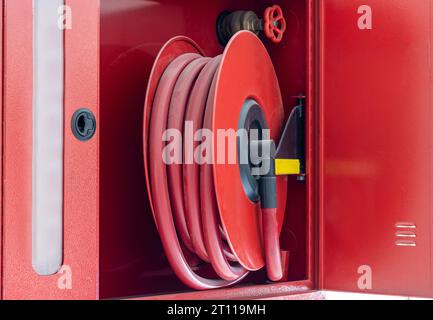 Feuerlöscher, roter Wasserschlauch an der Wand. Gebäude-Brandunterdrückungsanlage Stockfoto