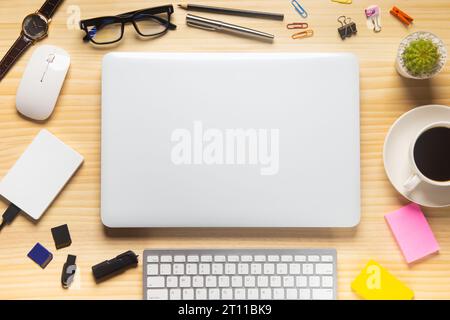 Holzschreibtischbüro mit Laptop, Smartphone und anderen Arbeitsmaterialien mit einer Tasse Kaffee. Draufsicht mit Kopierraum für die Texteingabe. Arbeitsbereich des Konstrukteurs o Stockfoto