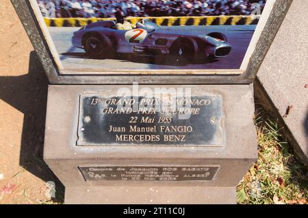 Gedenkstein und Gedenktafel mit Foto zur Feier von Juan Manuel Fangio, der das erste Jahrzehnt des Formel-1-Rennens dominierte. In der Nähe der Grand Prix Strecke von Monaco und einer Skulptur von Fangio mit seinem Mercedes-Benz Auto. (135) Stockfoto