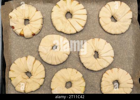 Draufsicht auf Apfelringe im Teig auf Backpapier. Hausmannskost. Stockfoto