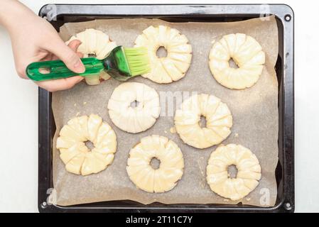 Eierdotter vor dem Backen über Apfelringe im Teig bestreichen. Hausmannskost. Stockfoto