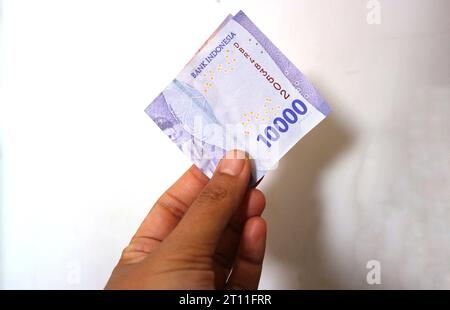 Batu City, Ost-Java, Indonesien. 20. Oktober ,2023: Ein Mann hält indonesisches Geld in zehntausend Rupien Stockfoto