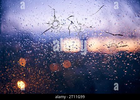 Schusslöcher im Glas vor dem Hintergrund einer verschwommenen Nahaufnahme der Stadt Stockfoto