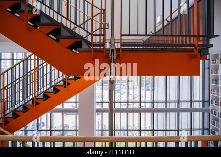 Seitenansicht einer Stahltreppe, die in intensiven Farben lackiert ist. Es sieht robust aus, da das Gewicht von silbernen Stahlstangen getragen wird. Stockfoto