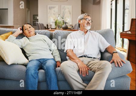 Seniorenpaar, wütend und Sofa im Wohnzimmer zu Hause, denken oder frustriertes Gesicht für Konflikt im Ruhestand. Älterer asiatischer Mann, alte Frau und Stress Stockfoto