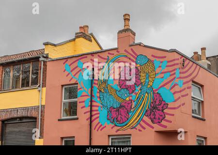 Bristol, Vereinigtes Königreich - 17. April 2023 - Rosa bemalter Hausgiebel mit blau-weißen Graffiti-Wandbildern an einer Ecke Stockfoto