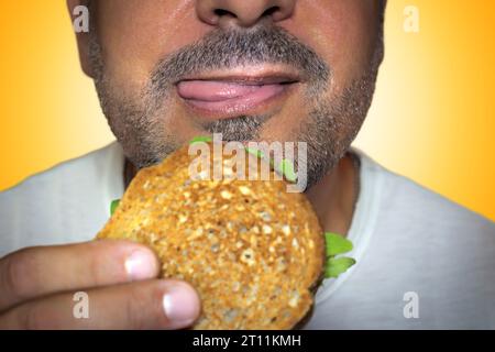 Unwiderstehliches Verlangen nach Junk Food. Nahaufnahme eines hungrigen Mannes, der in einen Käsetoast beißt. Stockfoto