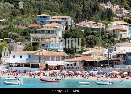 Agios Nikitas Fischerdorf, Lefkada (Lefkas), Ionische Inseln, Griechenland. Weite Aufnahme des geschäftigen Dorfes am Strand, der typische Familienurlaub zeigt Stockfoto