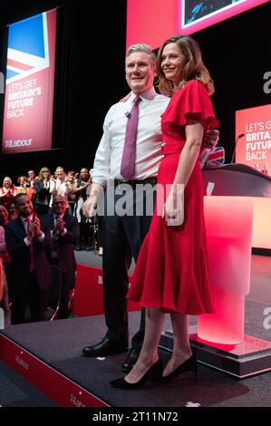 Victoria Starmer schließt sich Keir Starmer an, der zu Beginn der Rede mit Glitzer bedeckt war. Der Demonstrant wurde zu Boden geringt und von Sicherheitskräften entfernt. Sir Keir bürstete sich die Haare, zog seine Jacke aus und hielt die Rede fort. Sein Hemd, seine Hände und der Boden um ihn herum waren mit Glitzer bedeckt und blieben es während der gesamten Rede. Seine Frau Victoria Starmer applaudierte seine Rede durch und schloss sich ihm am Ende der Rede an. Arbeitskonferenz 2023. Bild: Garyroberts/worldwidefeatures.com Stockfoto