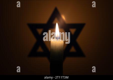 Brennende Kerze auf dem Hintergrund der israelischen Flagge. Internationaler Holocaust-Gedenktag, 27. Januar. Krieg im Nahen Osten Stockfoto