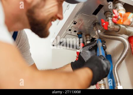 Nahaufnahme des Klempners mit Schraubendreher während der Installation neuer Stahl-Warmwasser-Zentralheizung in der Wohnung Stockfoto