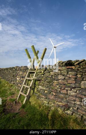 Holzstiel über Trockenmauer mit einer Windturbine dahinter Stockfoto