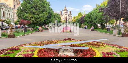 Hauptplatz in der Stadt Târgu Mureș in Siebenbürgen, Rumänien mit großem Blumenbeet und Sonnenuhr im Vordergrund. Stockfoto