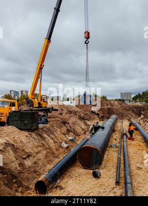 Verfahren zur Verlegung und Verbindung von Wasserversorgungs- oder Abwasserleitungen. Hebevorgänge im Bauwesen. Stockfoto