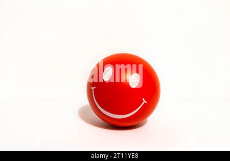 Roter Stressball mit Lächeln. Durch Drücken dieser Taste können die Menschen ihren Stress loswerden und sich entspannen. Stockfoto