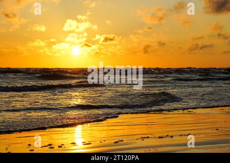 Ein schöner heller goldener Sonnenuntergang am Ufer der Ostsee, goldener Sonnenuntergang am Meer Stockfoto