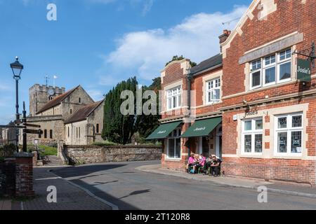 St. Peters Church in Petersfield, Hampshire, England, Großbritannien, von der St. Peter's Road aus gesehen, mit Leuten, die vor Josie's Coffee Shop sitzen Stockfoto