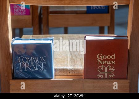 Lobliederbuch und Bibel der Guten Nachrichten auf Kirchenbänken, Großbritannien Stockfoto