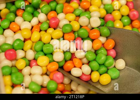 Auf der Theke stehen Süßigkeiten - Erdnüsse in mehrfarbiger Glasur und eine Schaufel. Süßwarenladen. Stockfoto