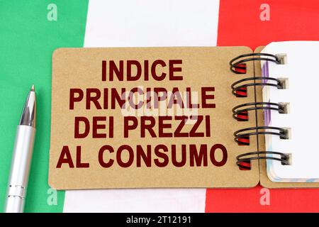 Wirtschafts- und Finanzkonzept. Auf der Flagge Italiens befinden sich ein Stift und ein Notizbuch mit der Aufschrift "Core Consumer Price Index". Text auf Italienisch. Stockfoto