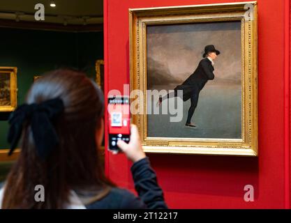 Besucher fotografieren das ikonische schottische Gemälde des Reverend Robert Walker Skating am Duddingston Loch von Sir Henry Rayburn im Scottish National G Stockfoto