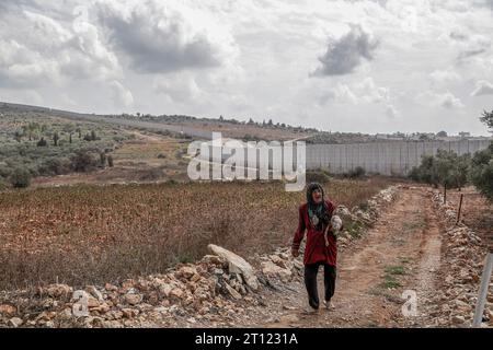 Dhaira, Libanon. Oktober 2023. Eine ältere libanesische Frau läuft in der Nähe einer israelischen Grenzmauer im südlibanesischen Dorf Dhaira, wo palästinensische Militante einen israelischen Posten angreifen und Israel reagierte, indem er das Dorf tötete und drei pro-iranische Hisbollah-Kämpfer tötete. Marwan Naamani/dpa/Alamy Live News Stockfoto