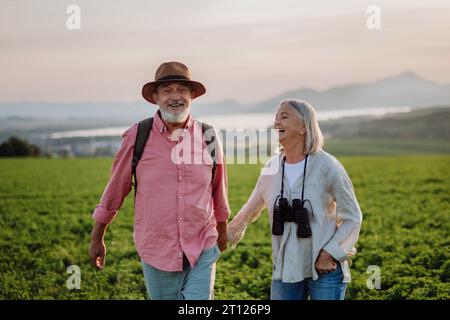 Porträt eines Seniorenpaares, das durch die herbstliche Natur geht und Pilze sammelt. Stockfoto