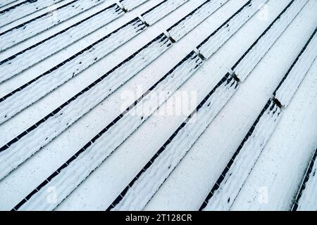 Luftaufnahme eines schneebedeckten nachhaltigen Elektrizitätswerks mit Reihen von Photovoltaik-Solarzellen zur Erzeugung sauberer elektrischer Energie. Niedrig Stockfoto