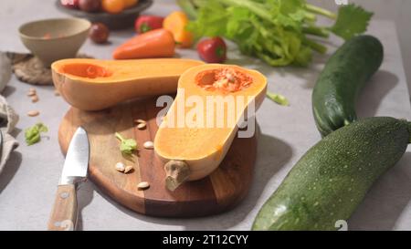 Herbstgemüse auf einer Küchenarbeitsfläche angeordnet, während eine Kürbissuppe zubereitet wird. Stockfoto