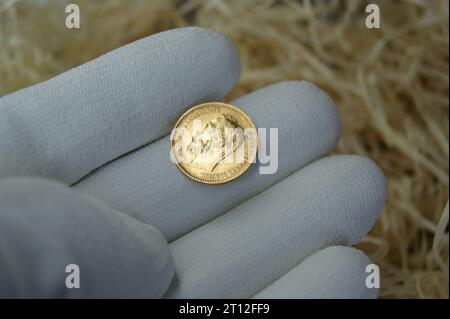 Eine Goldmünze des Russischen Reiches in der Hand eines Numismatikers. Numismatik und Investitionen. Stockfoto