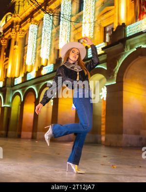 Winterstil, junges weißes blondes Model mit Jeans und schwarzer Jacke in der Stadt, die nachts zu weihnachten beleuchtet wird Stockfoto
