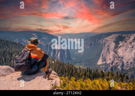 Ein junger Mann auf der Wanderung, der auf dem Aussichtspunkt Sentinel Dome im Yosemite-Nationalpark sitzt und den El Capitan Mountain betrachtet. Usa Stockfoto