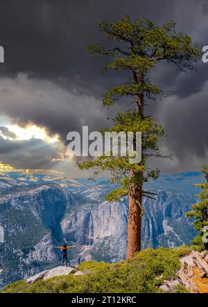 Eine junge Frau im Sentinel Dome mit Blick auf den Upper Yosemite Fall, Yosemite National Park. Usa Stockfoto