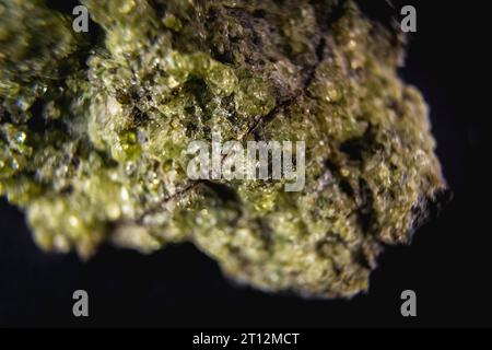 Stein mit einem sehr schönen grünen Mineral mit schwarzem Hintergrund. Makrofotografie Stockfoto