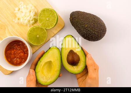 Avocadoschnitt mit Limetten-, Tomaten- und Zwiebelsauce. Rezept zur Zubereitung einer Guacamole Stockfoto