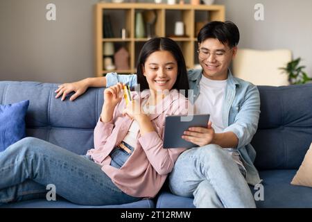 Koreanischer Mann und koreanische Frau, die über Tablet-Indoor einkaufen Stockfoto