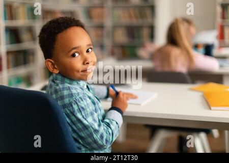 Lächelnder afroamerikanischer Junge in der Klasse, der sich zurück zur Kamera dreht Stockfoto