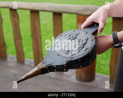 Alte handgemachte Kaminbalge in den Händen von Menschen, selektiver Fokus. Dekoriertes Vintage-Paar Balg, ein Gerät zum Erzeugen eines Luftstrahls Stockfoto