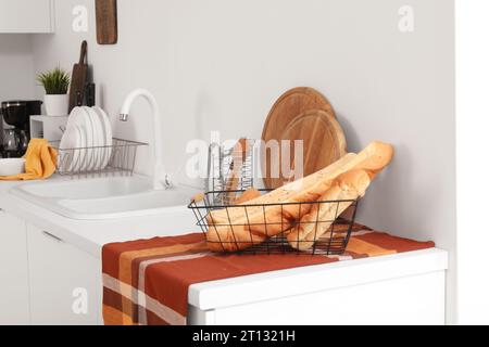 Korb mit frischen Baguettes und Schneidebrettern auf weißer Küchenzeile Stockfoto