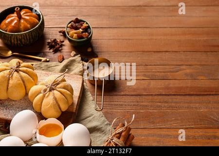 Brett mit Kürbisbrötchen und Zutaten auf hölzernem Hintergrund Stockfoto