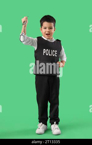 Netter kleiner Polizist mit Handschellen auf grünem Hintergrund Stockfoto