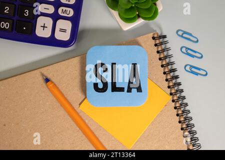 Geschäftskonzept – Wort SLA auf Haftnotizpapier auf schwarzem Tastaturhintergrund geschrieben. sla-Abkürzung für Service Level Agreement. Stockfoto