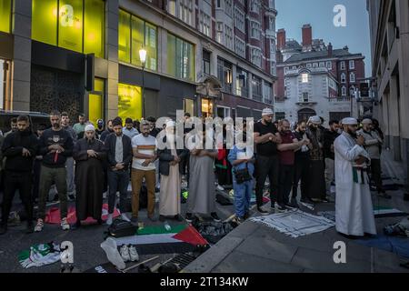 London, Großbritannien. Oktober 2023. Während des Protestes werden Gebete gehalten. Anhänger Palästinas treffen sich zu einer Massendemonstration in der Nähe der israelischen Botschaft in der High Street Kensington, die von der „Stop the war“-Koalition organisiert wurde. Die Demonstranten skandierten „Israel ist ein terroristischer Staat“ und „freies Palästina“, während sie Fackeln und Feuerwerk losließen. Am 7. Oktober startete die Hamas einen Überraschungsangriff aus Gaza auf Israel. Der israelische Premierminister Benjamin Netanjahu hat erklärt, dass Israel im Krieg ist. Guy Corbishley/Alamy Live News Stockfoto