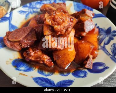 Geschmortes Schweinefleisch mit Kartoffeln auf der blauen Platte zum Essen Stockfoto