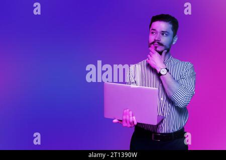 Schöner Mann mit Laptop in Neonlichtern, Platz für Text Stockfoto