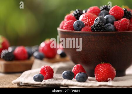 Schüssel und verschiedene frisch reife Beeren auf dem Tisch draußen, Nahaufnahme Stockfoto
