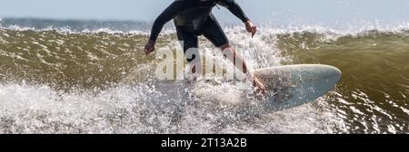 Vorderansicht eines Mannes, der in rauen Wellen am Gilgo Beach auf Long Island surft und planscht. Stockfoto